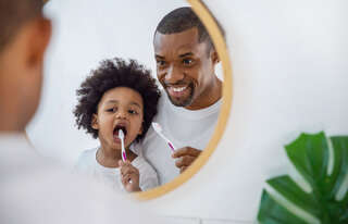 happy family black african father and son child boy brushing teeth