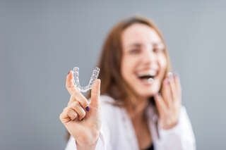 beautiful smiling turkish woman is holding an invisalign bracer